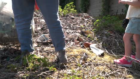 madre e hija caminando sobre la basura mientras sostienen una bolsa de plástico llena de basura