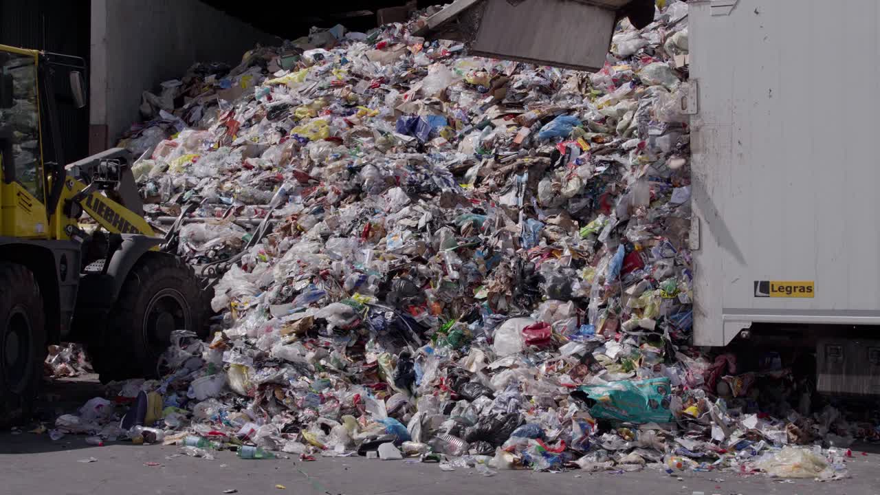 en un centro de reciclaje, descarga de un camión de residuos, proceso de gestión y eliminación de materiales de desecho, transferencia de los residuos a un sitio designado de eliminación o procesamiento