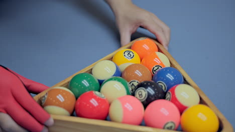 billiard player hands with gloves levels the pyramid of balls and remove the triangle