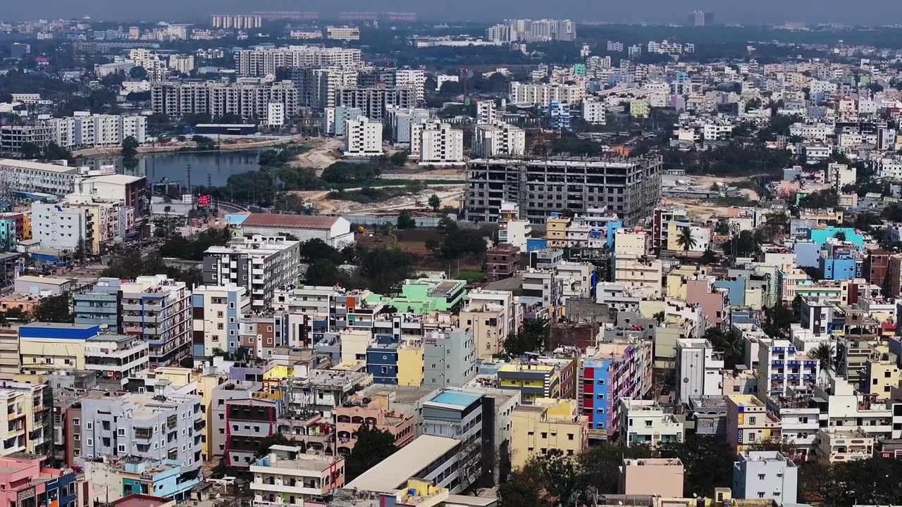 Lago Kattamysamma con edifici in costruzione, appartamenti ed edifici residenziali a Suraram, Jeedimetla, Hyderabad, Telangana, India. Di giorno, ripresa all'indietro, ripresa con drone, 4k