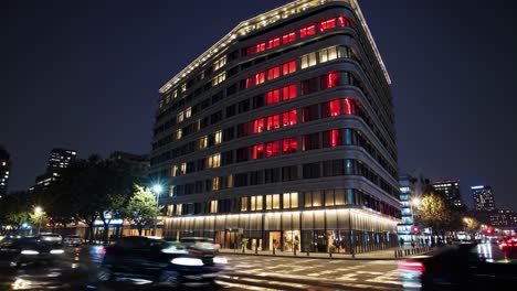 a modern hotel building at night with glowing windows and a mysterious dark force presence. the wet street reflects city lights as blurred cars pass by, adding to the eerie atmosphere