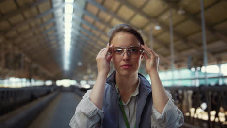 portrait livestock worker posing in cowshed. agriculture manager put on glasses.