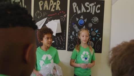 two girls wearing recycle symbol tshirt holding plastic bottle and bag