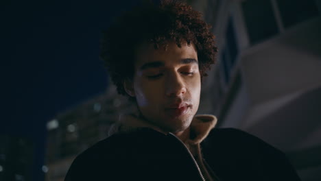 thoughtful zoomer relaxing night town alone closeup. latin guy nightlife