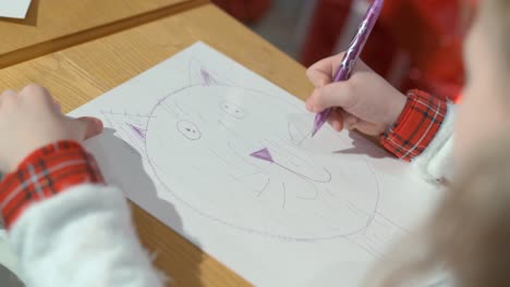 a girl draws a kitten on paper with a pencil. close-up of hands. the child is learning to draw