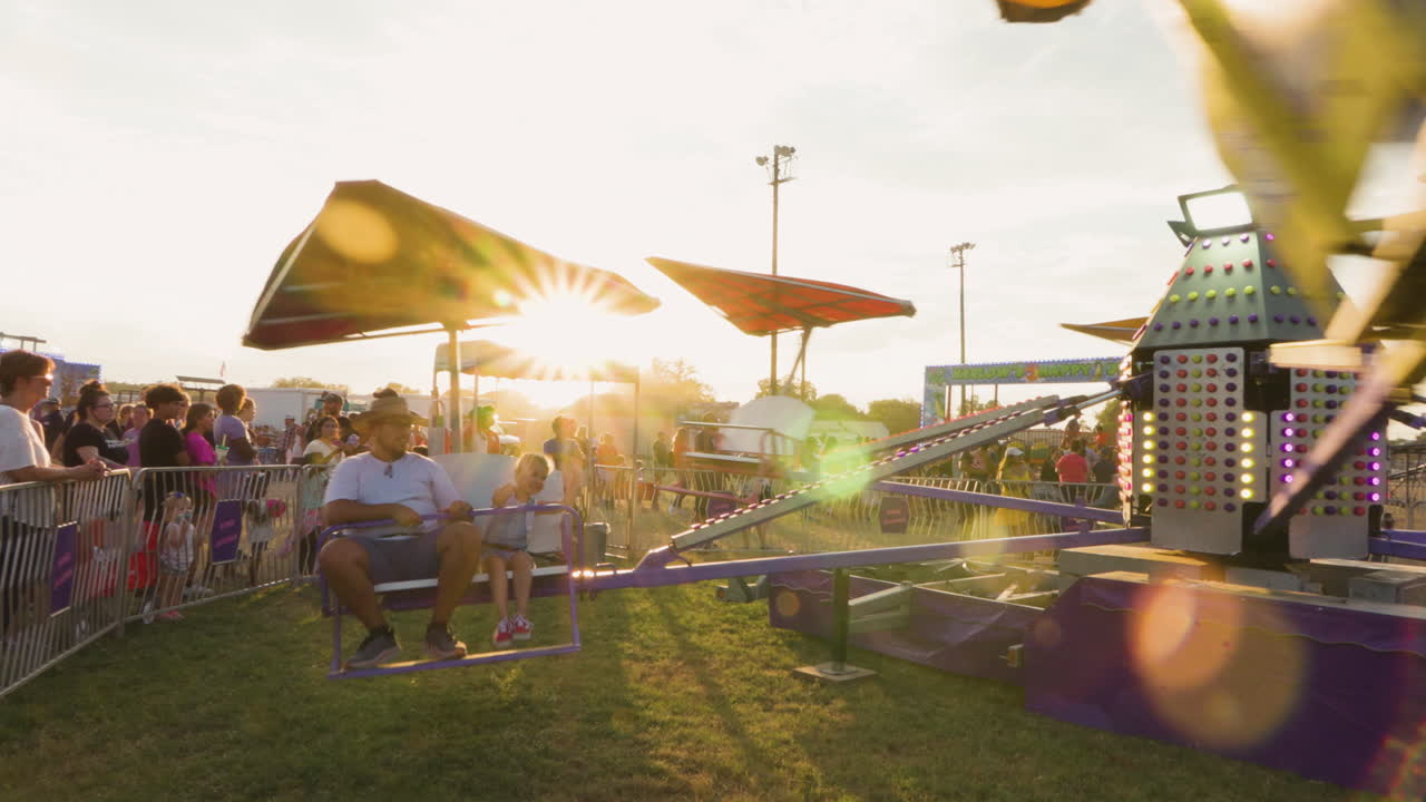A carnival ride spins with kids aboard, lights flashing vibrantly against the setting sun, capturing the magical blend of thrill and twilight ambiance.