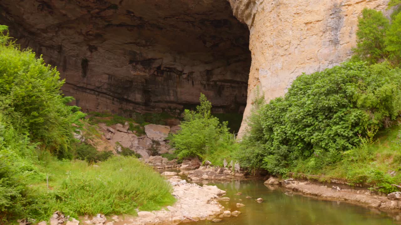 Cave entrance with lush greenery in Mas d'Azil, France, serene and natural