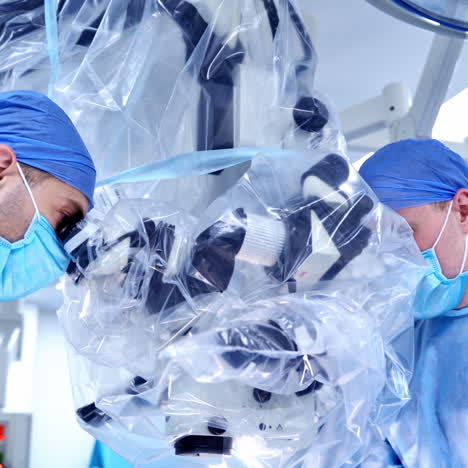 closeup of two surgeons with operating microscope. health treatment concept.