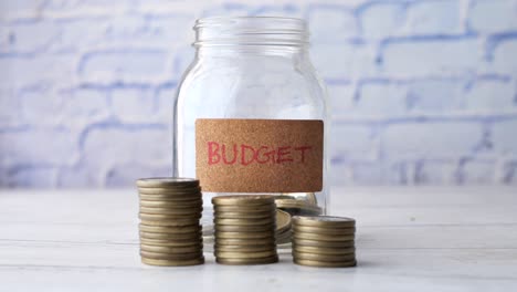 budget text on a saving coins jar on white ,