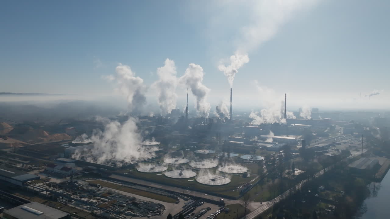 Ampio panorama aereo che mostra la grande cartiera e gli impianti industriali a Štětí con diverse ciminiere e fitte nuvole di vapore che si estendono su un orizzonte fosco