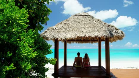 caucasian couple sitting in a tiki beach hut