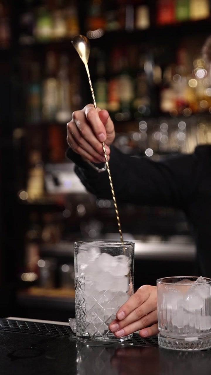 Nærbillede af bartender, der rører is i et glas med en barske