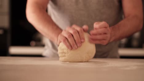 man of the house flouring pizza dough on countertop in home kitchen and kneading it