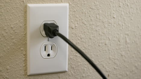 Close-Up-Side-of-Man's-Hand-Plugging-Cord-Into-Electrical-Outlet-Then-Unplugging-in-Real-Time