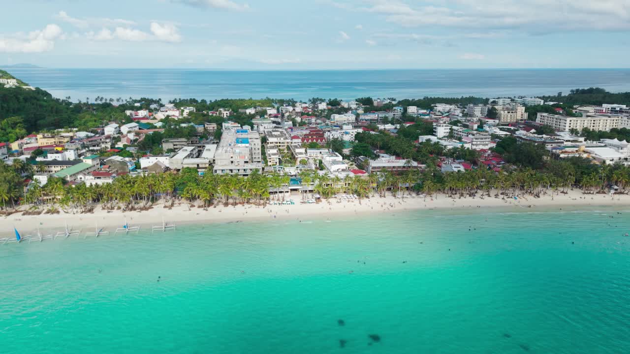 Inquadratura cinematografica di ambientazione di mare turchese, barche a vela, skyline di resort tropicale