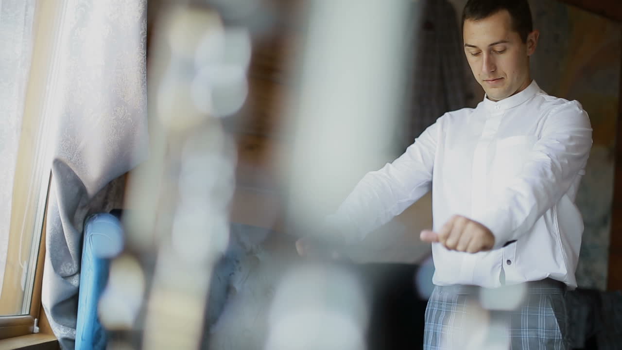 Un uomo indossa una camicia bianca. Bello sposo che si veste e si prepara per il matrimonio