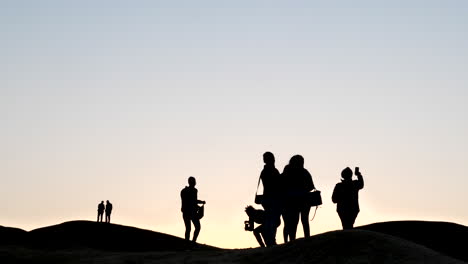 Plano-Amplio-De-Personas-En-Silueta-Contra-Un-Cielo-Rosado-En-El-Desierto-De-Namib-Al-Atardecer