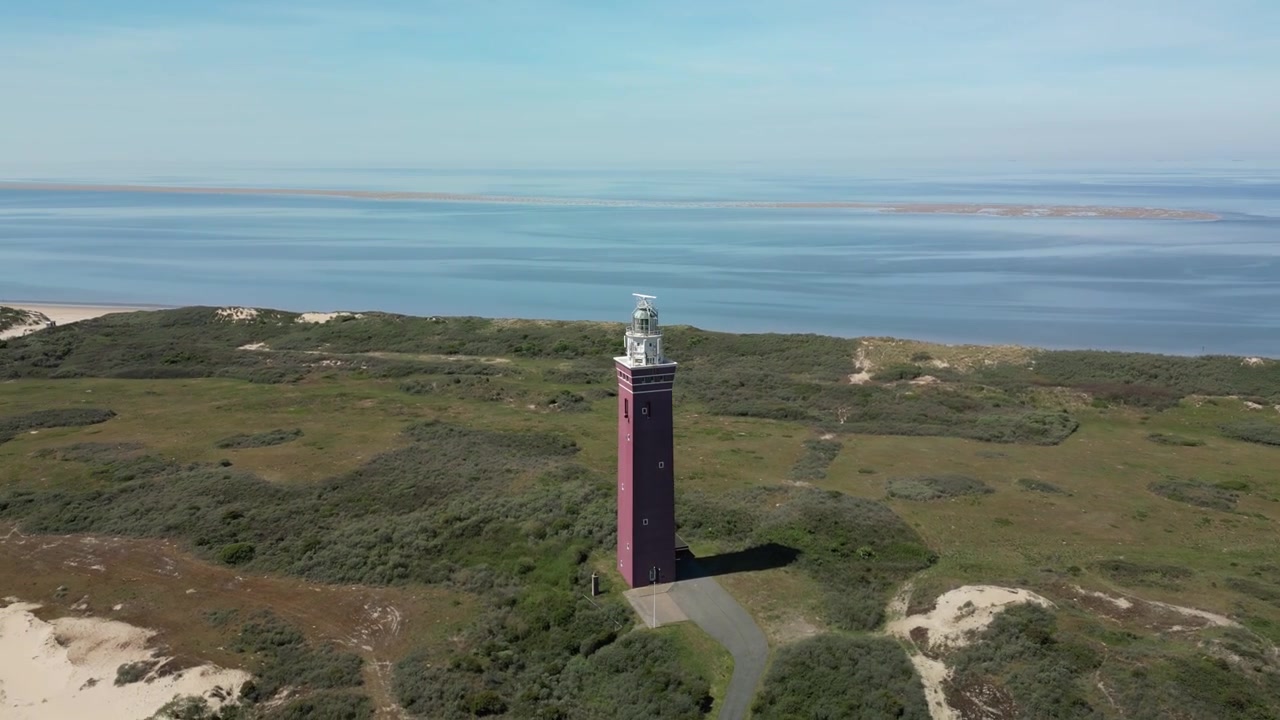 Un dron rodea el faro de Westhoofd en Holanda, una torre cuadrada distintiva con una casa de linterna blanca en la parte superior.