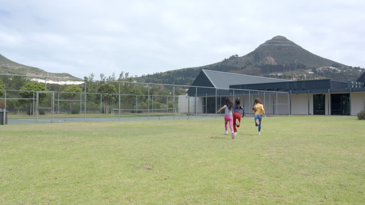 Running on school field, two girls enjoying outdoor activity together, copy space