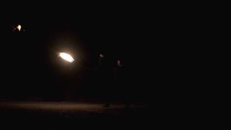 el tipo patea una cuerda con una llama al final. la cuerda vuela lejos y regresa. espectáculo de fuego. actuación nocturna. cámara lenta