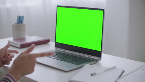 la mujer se está comunicando en línea por video chat en un portátil con pantalla verde para la tecnología de llave de croma vista de primer plano en la mesa