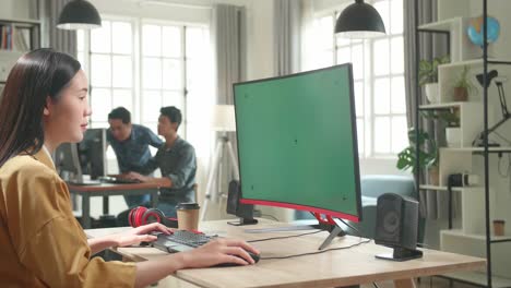asian female works with mock up green screen computer display in office