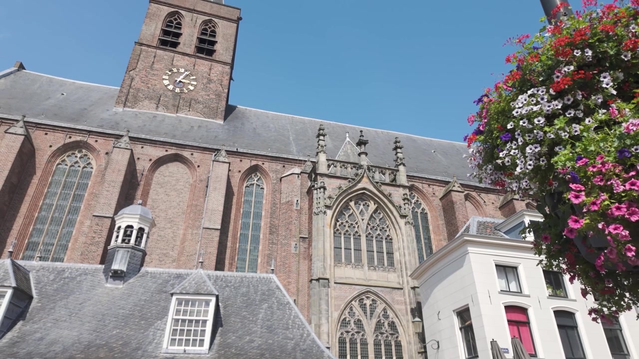 Igreja Sint-Joriskerk em Amersfoort, arquitetura histórica com flores penduradas, cenário urbano ensolarado