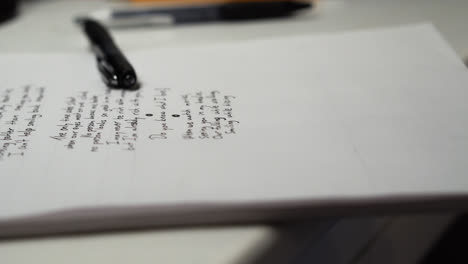 a black fountain pen laid on top of white paper board with unfinished love poem