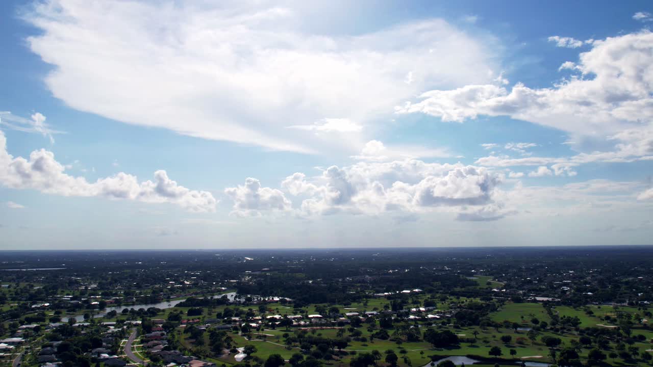 Beautiful aerial timelapse shot of sky over small community with  last sunlight through the clouds in summer evening; horizon line and sky gradient; community landscape
