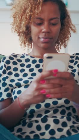 woman relaxing on couch focused on smartphone in cozy living room