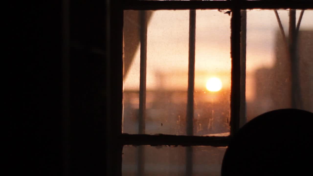 거울과 외부 장면 사이에 초점을 맞추는 둥근 거울 옆에 있는 창문을 통해 도시의 일몰