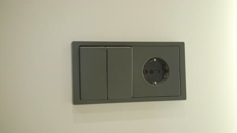 modern black light switch and power outlet on wall