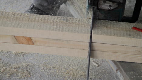 a worker cutting a wood beam during construction works