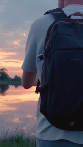 man hiking at sunset over a lake