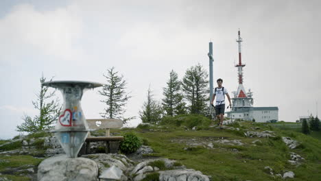 el caminante llega a la cima de la montaña y se detiene en el monumento y lo mira donde están escritas las direcciones