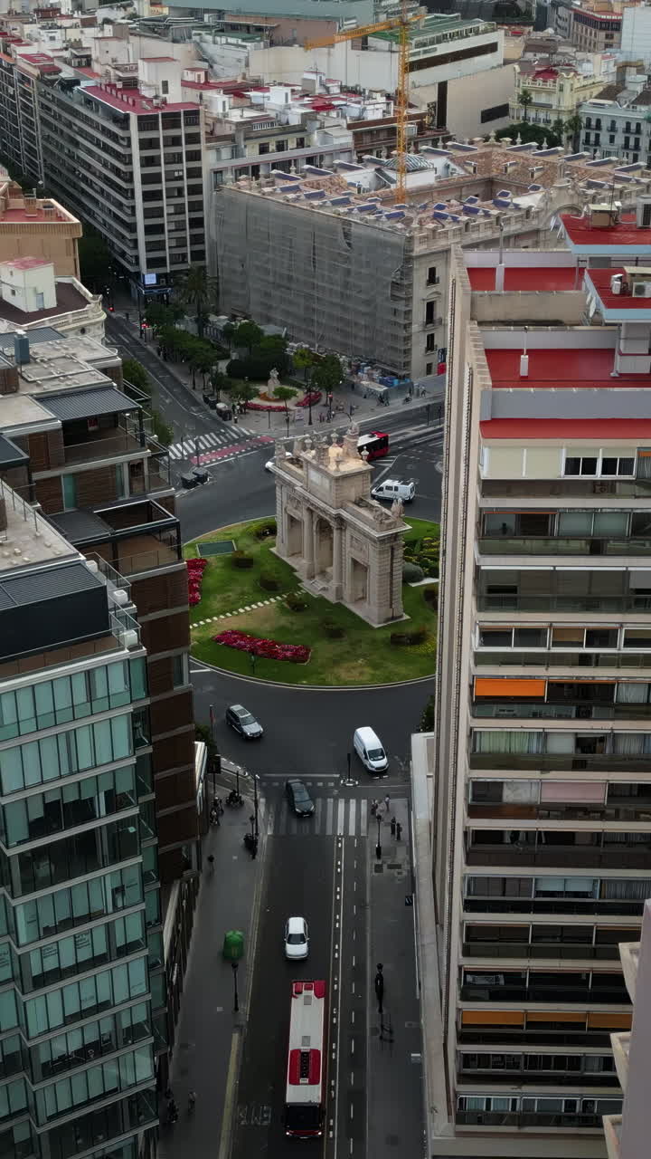 Aerial drone view of cars moving on the streets between the buildings, near Porta De La Mar in Valencia, Spain in daylight. Vertical