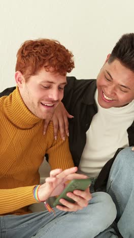 happy lgbtq+ couple smiling while using a smartphone