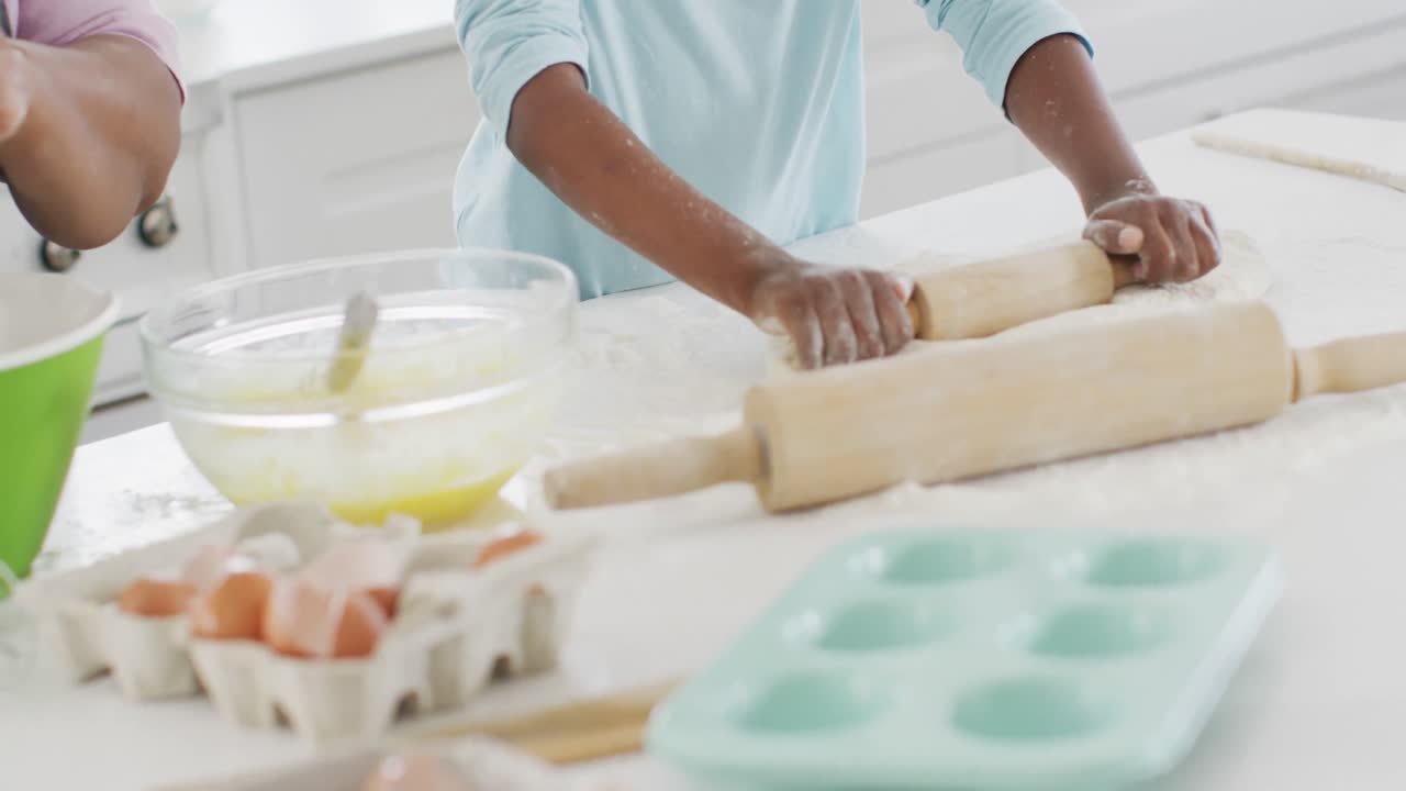Happy african american grandmother and granddaughter baking in kitchen, high fiving, copy space