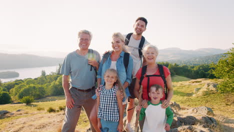 slow motion portrait of multi generation family standing at top of hill on hike through countryside in lake district uk