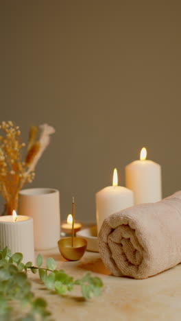 vertical video still life of lit candles with dried grasses incense stick and soft towels as part of relaxing spa day decor