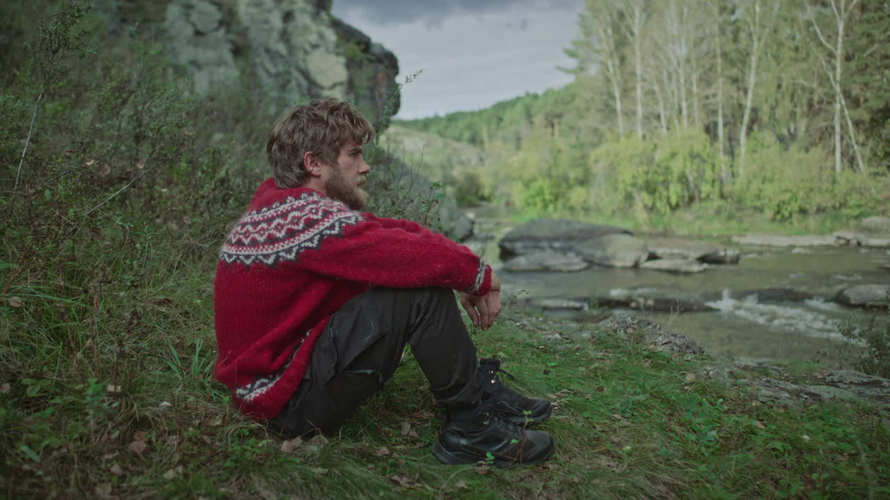Man Walking along Riverbank, Sitting on Grass and Enjoying Scenery