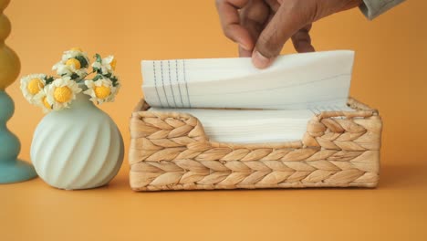 woven wicker napkin holder on a yellow background