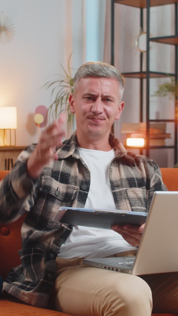 Uomo freelance stressato che rivede grafici e grafici aziendali e getta documenti e bollette non pagate in aria.