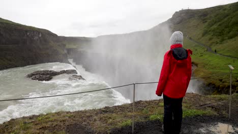 cataratas de gulfoss en islandia con video de cardán caminando detrás de una mujer mirando cataratas en cámara lenta