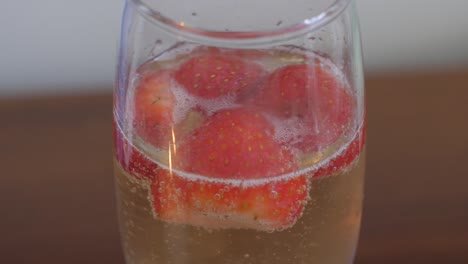 primer plano de fresas flotando en una copa de champán.