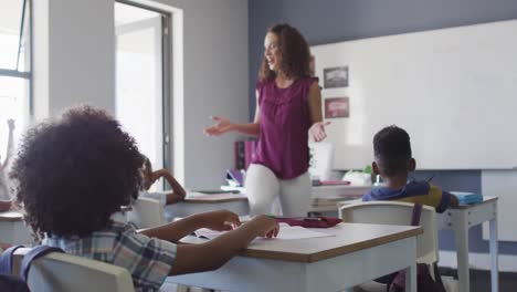 video of caucasian female teacher and diverse school children studying in classroom