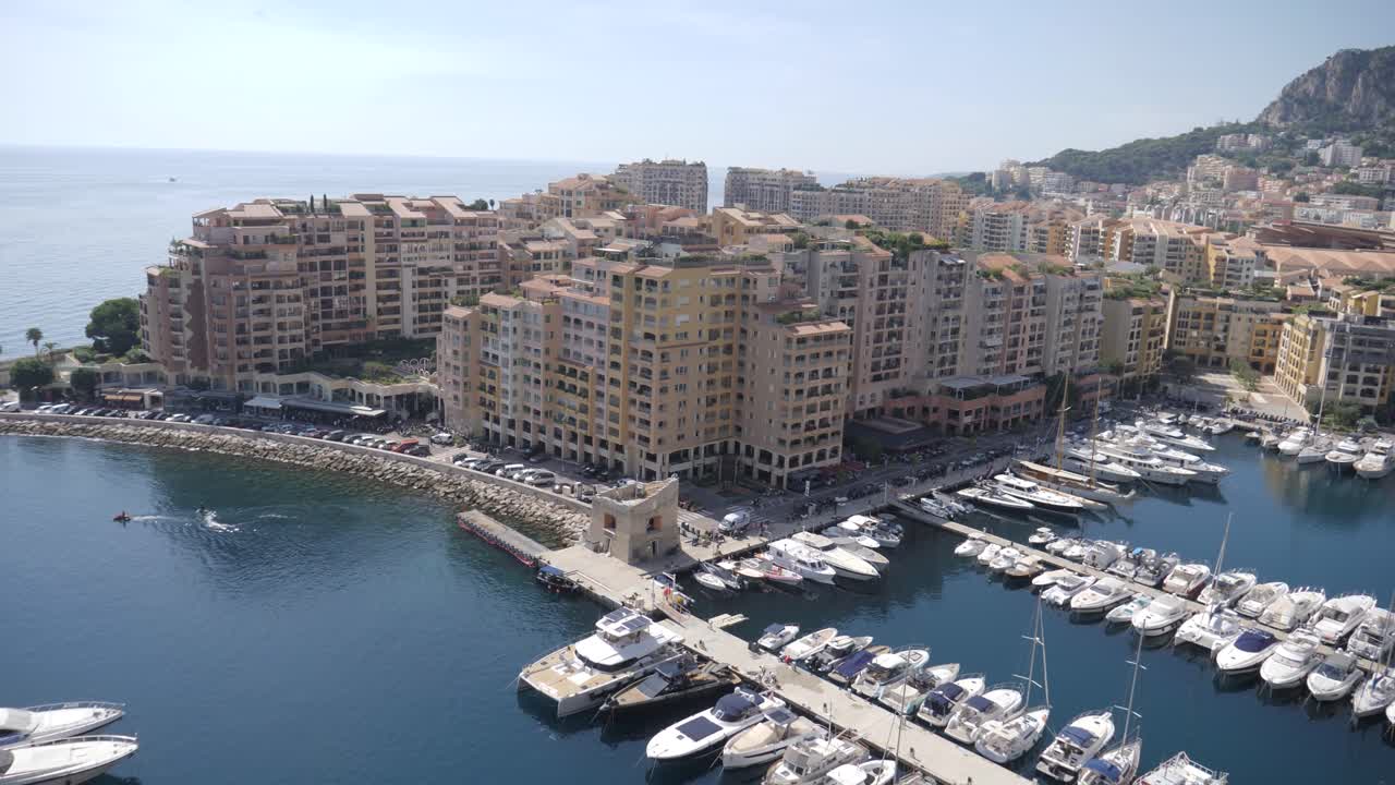 Vista di yacht di lusso ormeggiati nel porto di Fontvieille, Monaco. Appartamenti sul lungomare e un uccello che vola in primo piano in questo prestigioso porto turistico
