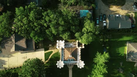 una toma de un dron de un lugar residencial junto con un edificio que parece un castillo con hiedra torre rodeada de árboles verdes