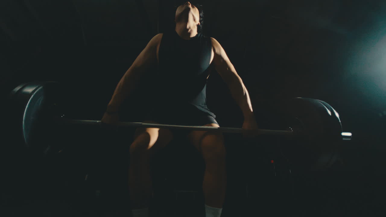 азиатская мужская сила очищает штангу в темном настроенном тренажерном зале, кросс-фит тренировка fisheye вытаскивает в 4k 800fps замедленное движение хватает тяжелый вес