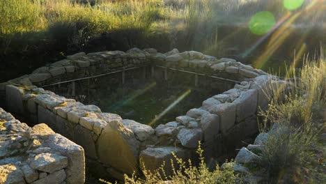 sun flare above stone wall embankment of archaeological ruins in ourense spain